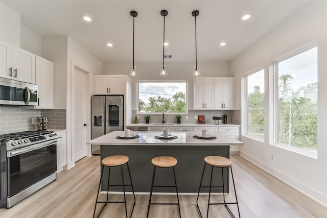 515 Egan St, Houston, TX 77020 - kitchen with stainless steel appliances, a kitchen bar, decorative backsplash, a center island, and white cabinetry