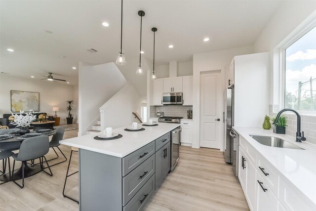 515 Egan St, Houston, TX 77020 - kitchen featuring stainless steel appliances, a sink, gray cabinets, decorative backsplash, and white cabinetry