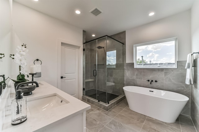 bathroom with visible vents, a freestanding bath, a stall shower, a sink, and recessed lighting
