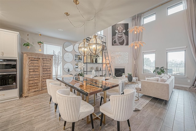 dining room featuring light hardwood / wood-style floors, an inviting chandelier, and a towering ceiling