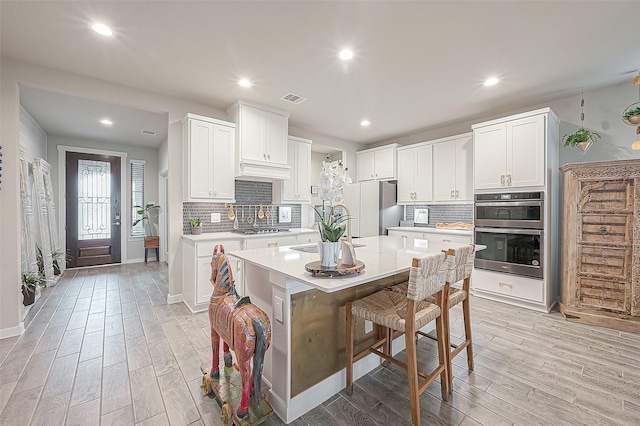 kitchen featuring white cabinetry, appliances with stainless steel finishes, a kitchen island, and a kitchen breakfast bar