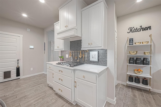 kitchen featuring white cabinetry, tasteful backsplash, light hardwood / wood-style flooring, and stainless steel gas stovetop