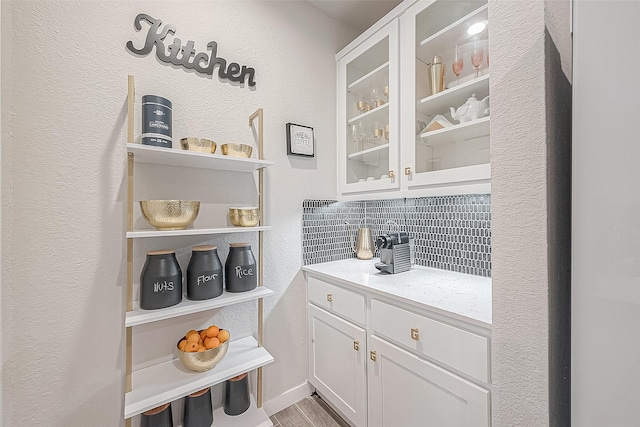 bar featuring hardwood / wood-style flooring, tasteful backsplash, and white cabinetry