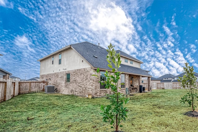 back of property with central AC and a lawn