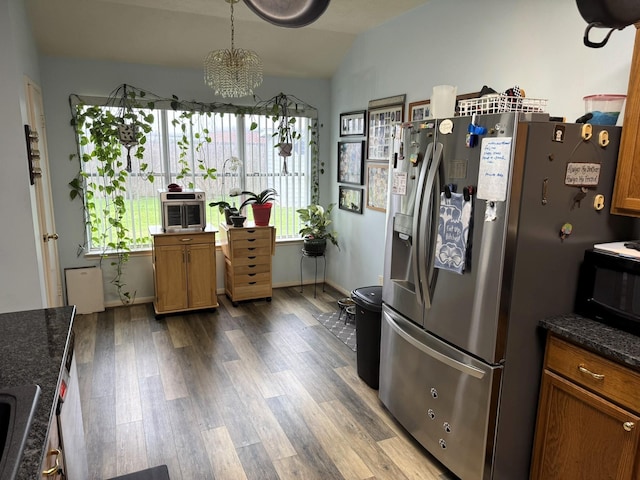 kitchen featuring dark hardwood / wood-style flooring, vaulted ceiling, stainless steel fridge with ice dispenser, and dark stone counters