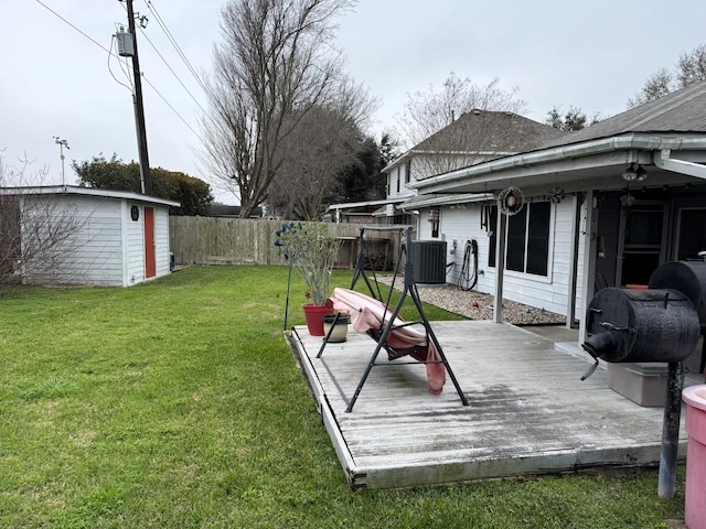 view of yard featuring a deck, central AC unit, and a storage shed