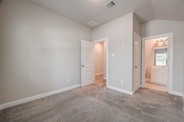 unfurnished bedroom featuring vaulted ceiling and light colored carpet