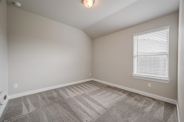 carpeted empty room featuring vaulted ceiling