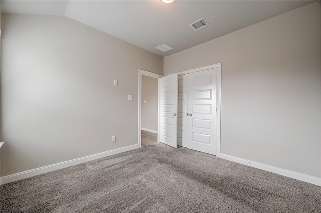 unfurnished bedroom with carpet, vaulted ceiling, and a closet