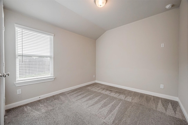 carpeted empty room with vaulted ceiling