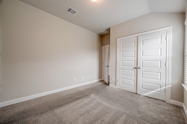 unfurnished bedroom featuring carpet, a closet, and vaulted ceiling