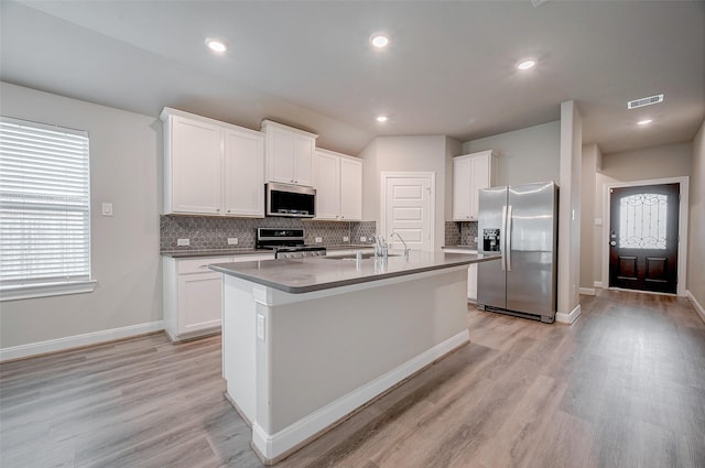 kitchen featuring light hardwood / wood-style flooring, appliances with stainless steel finishes, white cabinetry, and a kitchen island with sink