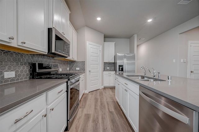 kitchen with stainless steel appliances, light hardwood / wood-style floors, sink, white cabinets, and decorative backsplash