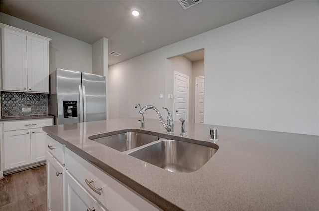 kitchen with white cabinets, sink, stainless steel fridge, and decorative backsplash