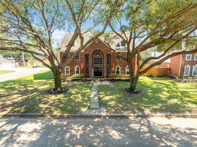 view of front of house featuring a front yard, fence, and brick siding