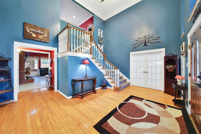 foyer entrance with french doors, stairway, a high ceiling, and wood finished floors