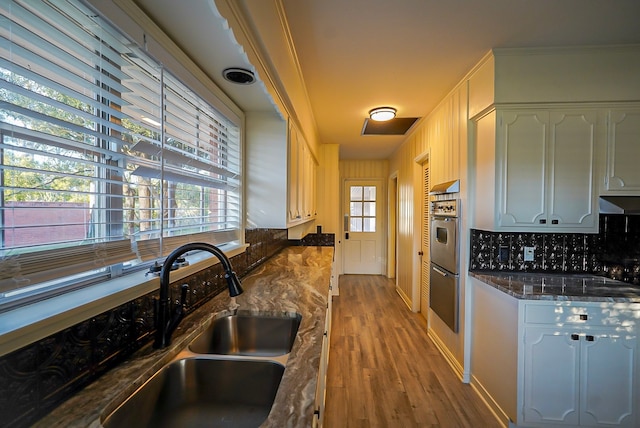 kitchen featuring white cabinets, light hardwood / wood-style floors, sink, and dark stone counters