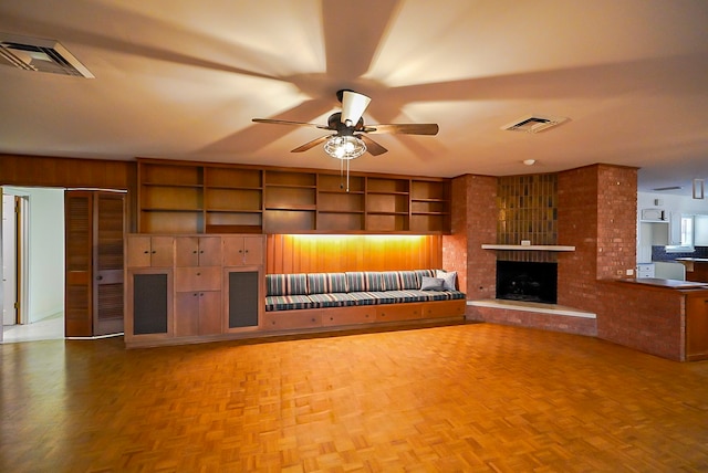 unfurnished living room with a brick fireplace, ceiling fan, and parquet floors