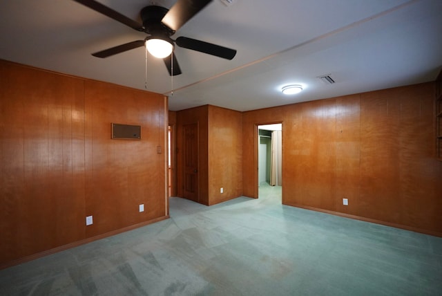 spare room with ceiling fan and wooden walls