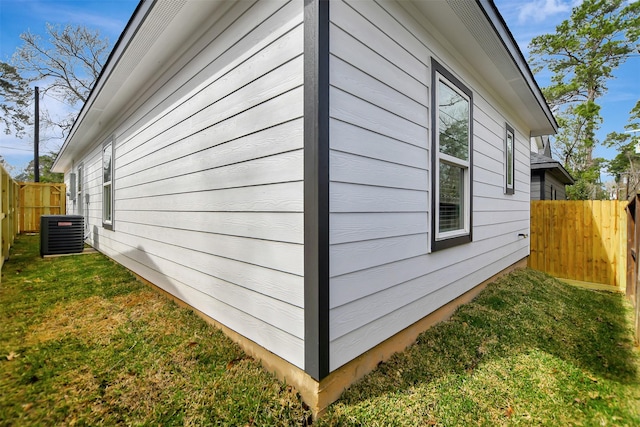 view of side of home with central AC unit and a yard