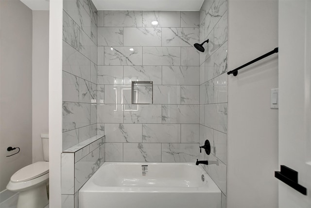 bathroom featuring tiled shower / bath combo and toilet