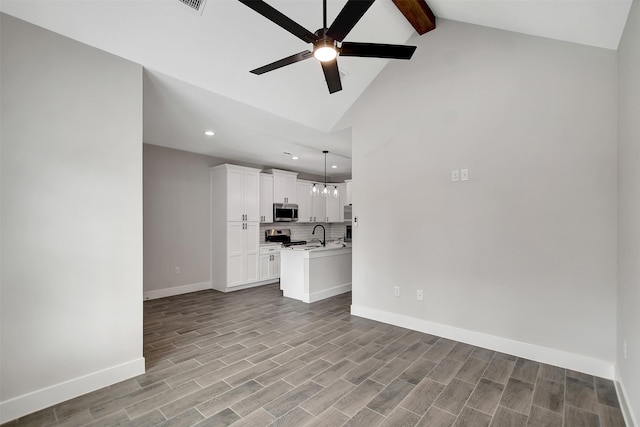 unfurnished living room featuring ceiling fan with notable chandelier, light hardwood / wood-style floors, high vaulted ceiling, and beam ceiling