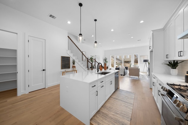 kitchen with an island with sink, open floor plan, stainless steel appliances, light countertops, and a sink