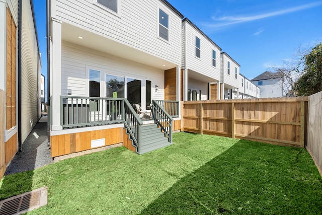 rear view of house with a yard, a fenced backyard, and a wooden deck