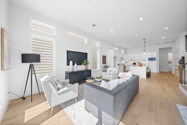 living area featuring light wood-type flooring, visible vents, baseboards, and recessed lighting