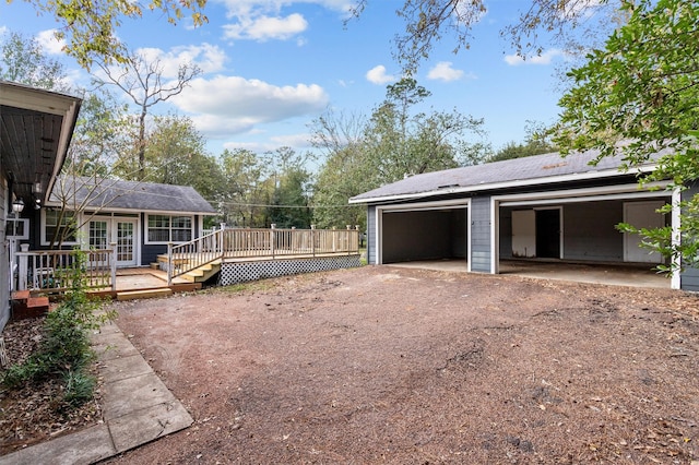 exterior space with a deck, a garage, and an outbuilding