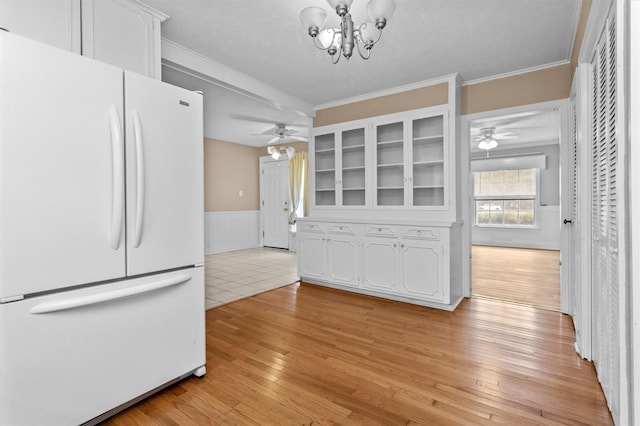 kitchen featuring white fridge, ceiling fan with notable chandelier, and white cabinets