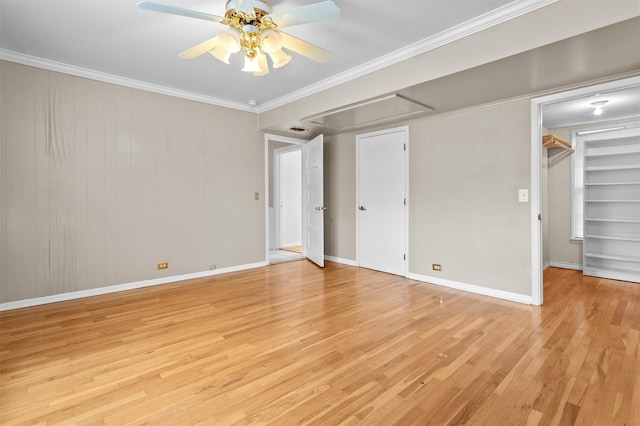 unfurnished bedroom featuring light hardwood / wood-style floors, a walk in closet, crown molding, and ceiling fan