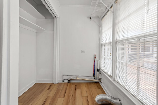 laundry area with light wood-type flooring and crown molding