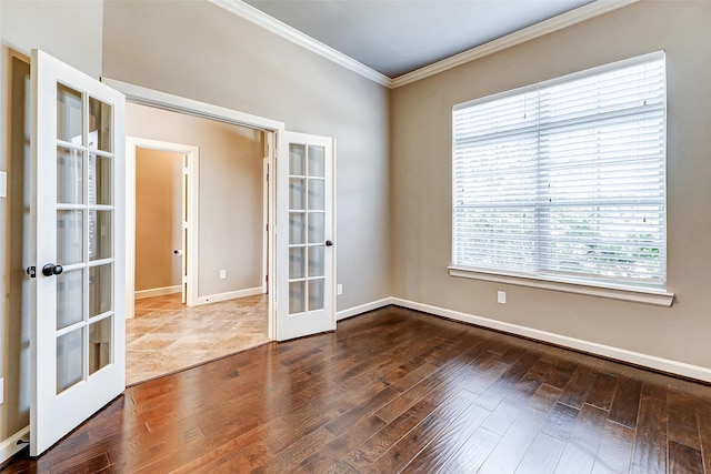 empty room with baseboards, ornamental molding, wood finished floors, and french doors