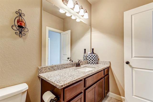 half bathroom with toilet, tile patterned flooring, vanity, and baseboards