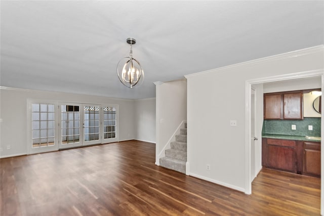 unfurnished living room featuring dark hardwood / wood-style flooring, ornamental molding, a chandelier, and french doors