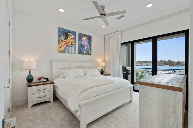 bedroom with recessed lighting, visible vents, a water view, light carpet, and access to outside