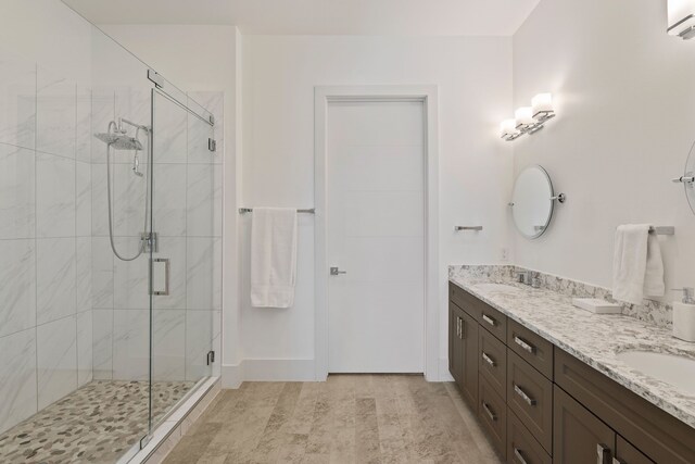 bathroom featuring a sink, a shower stall, and double vanity