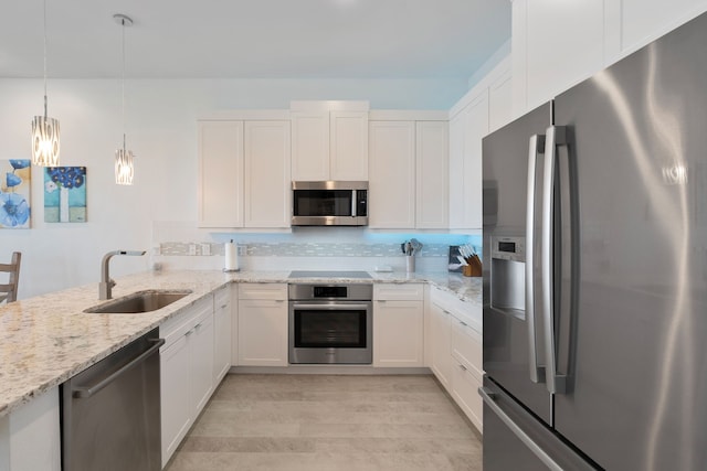 kitchen with light wood finished floors, tasteful backsplash, appliances with stainless steel finishes, white cabinetry, and a sink