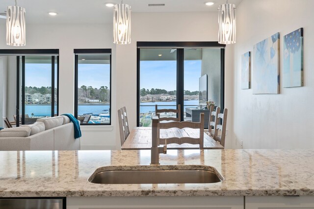 kitchen with light stone counters, open floor plan, a sink, and recessed lighting