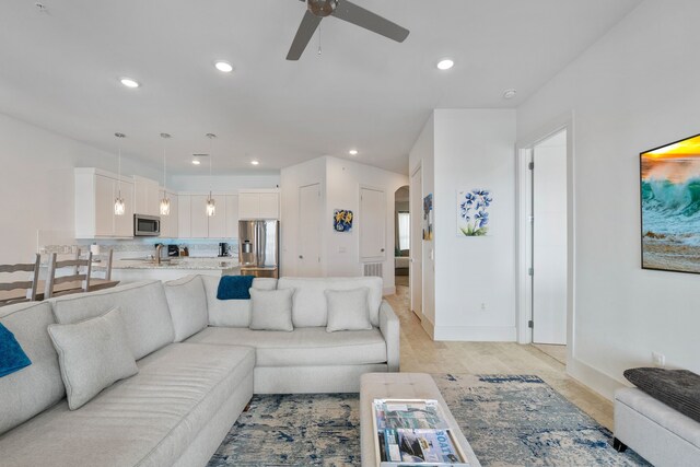 living room featuring baseboards, arched walkways, a ceiling fan, and recessed lighting