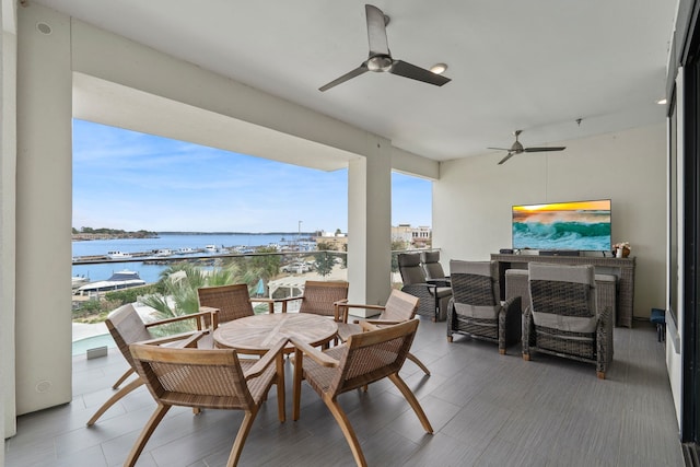 view of patio / terrace with a ceiling fan, outdoor dining area, and a water view