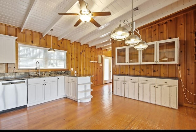 kitchen with stainless steel dishwasher, hanging light fixtures, white cabinets, and wooden walls