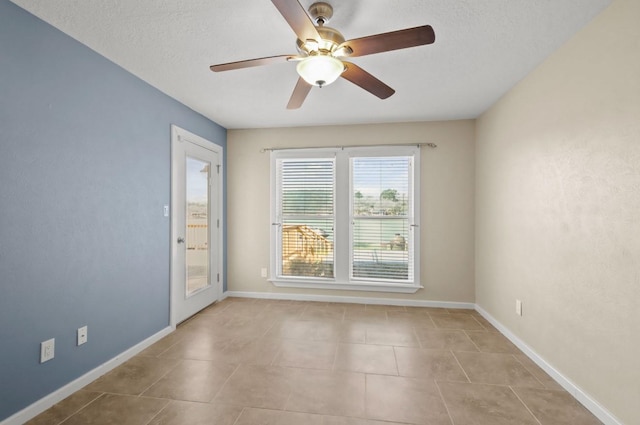 spare room featuring ceiling fan, light tile patterned flooring, and a textured ceiling