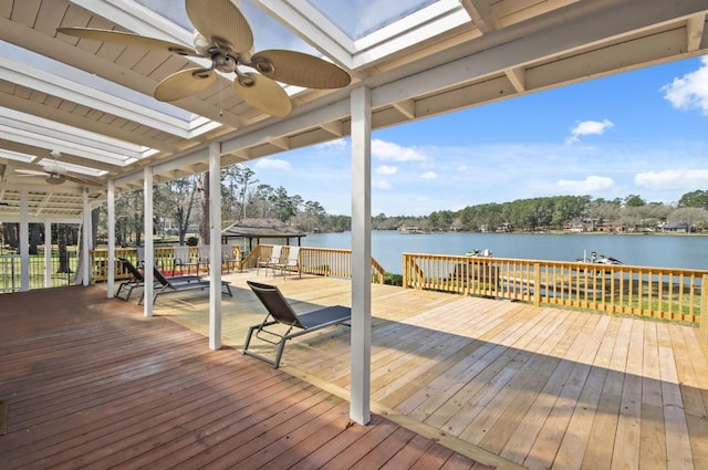 wooden terrace with a water view, ceiling fan, and a gazebo