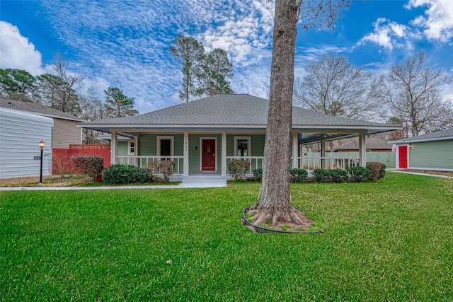 view of front facade with a porch, a front yard, a shingled roof, and fence