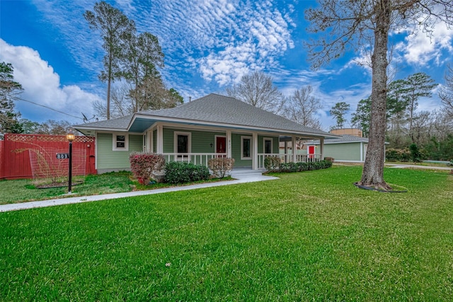 view of front of home featuring a shingled roof, fence, a porch, and a front yard