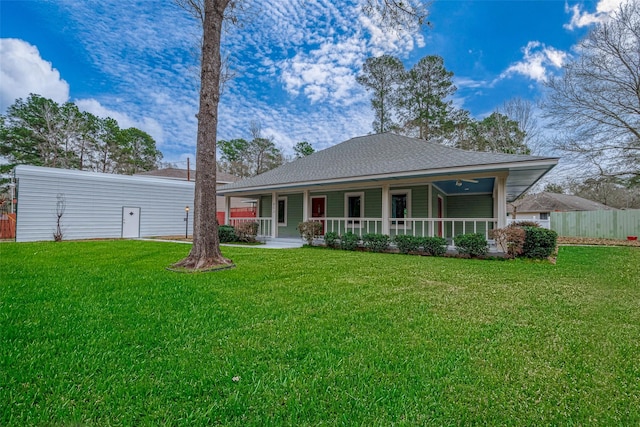 view of front of home with a shingled roof, covered porch, fence, and a front lawn