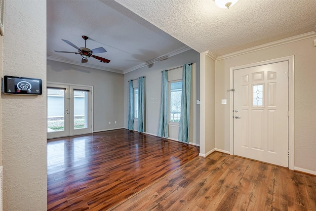 foyer entrance with a textured ceiling, wood finished floors, baseboards, french doors, and ornamental molding