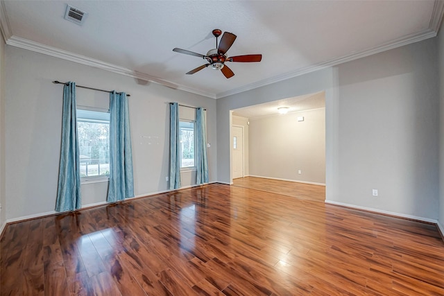 spare room featuring crown molding, wood finished floors, visible vents, and a ceiling fan